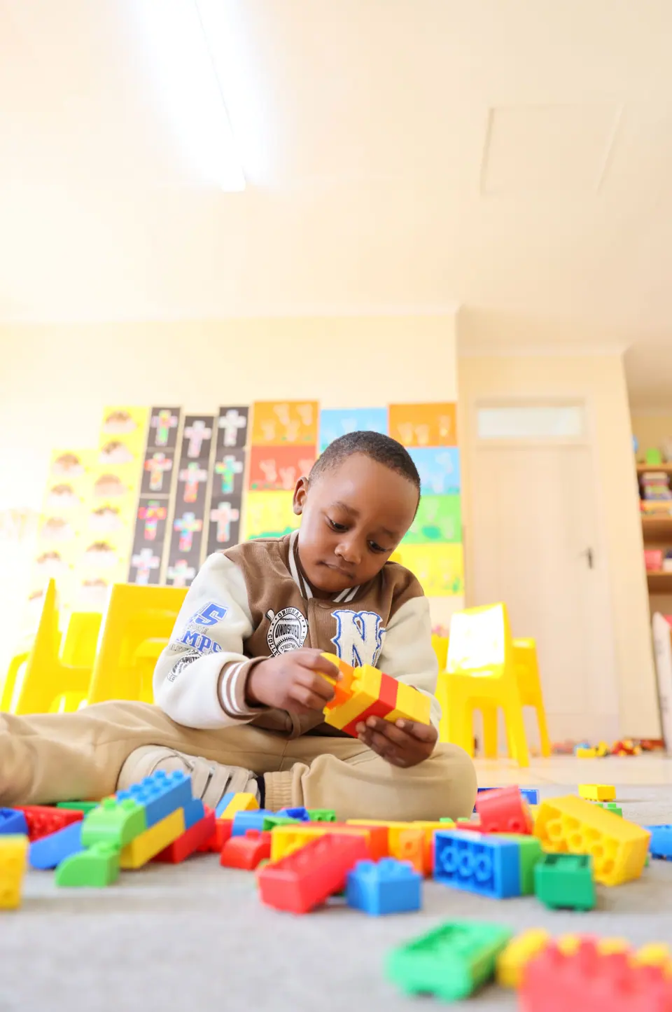 A boy building with chunky blocks on the classroom floor