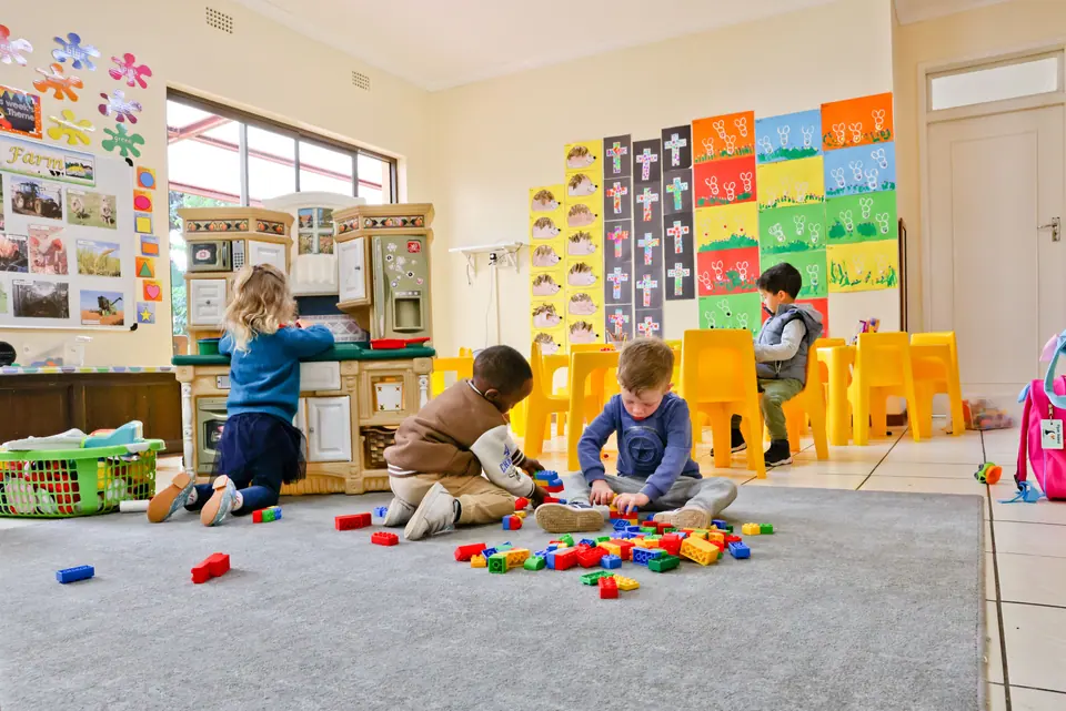 Children playing with blocks on the carpet of a bright classroom
