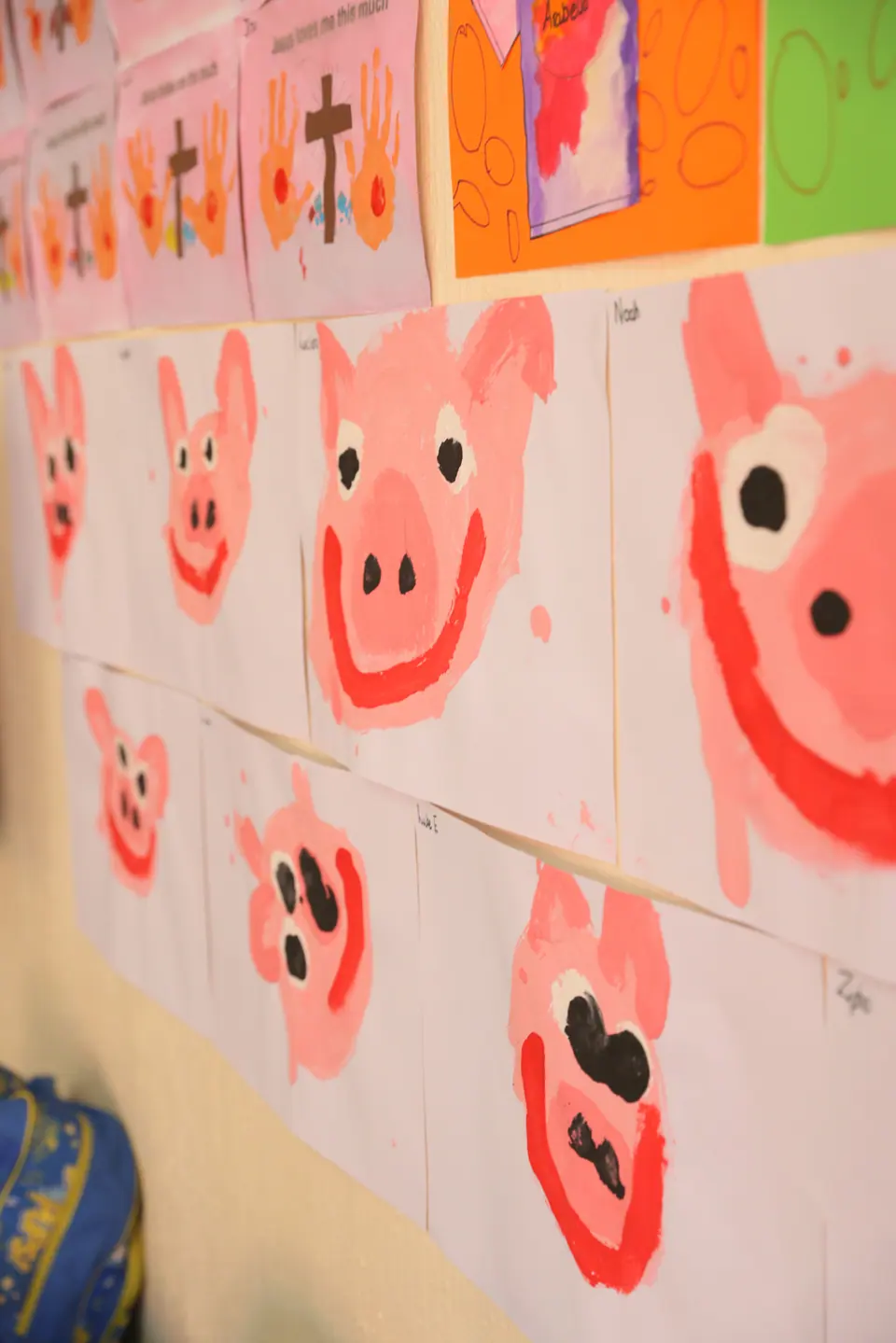 Children’s pig paintings displayed on the classroom wall