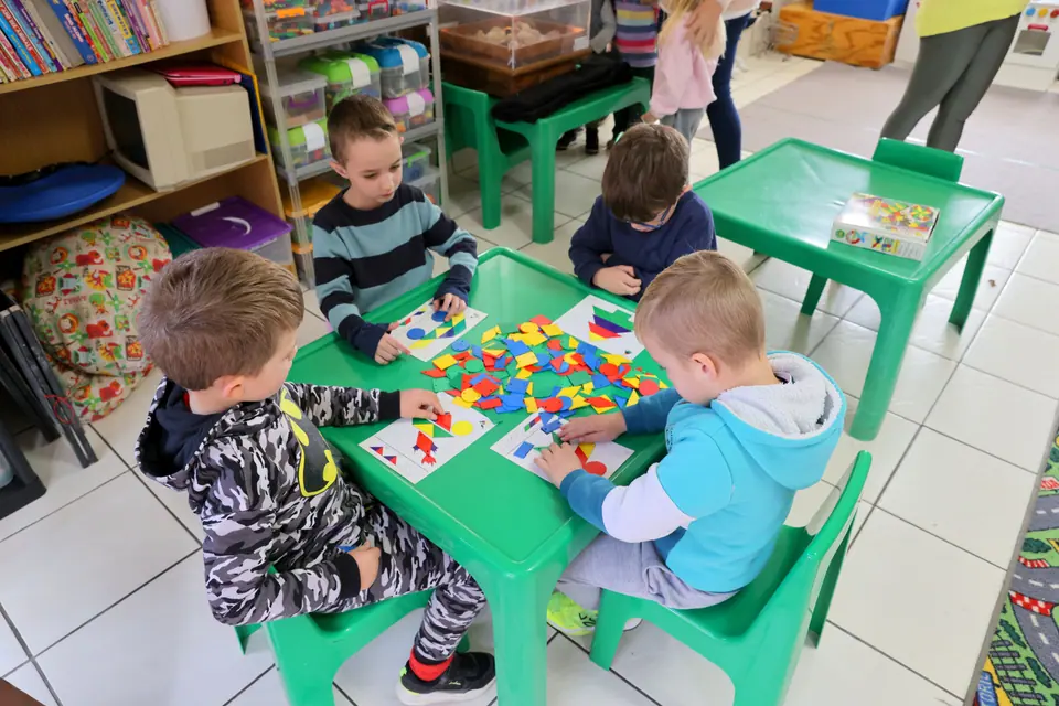 Children doing a puzzle activity together at a green table