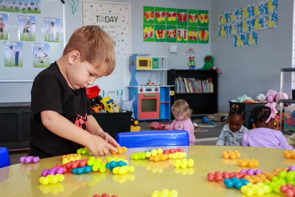 A boy sorting colourful beads at a classroom table
