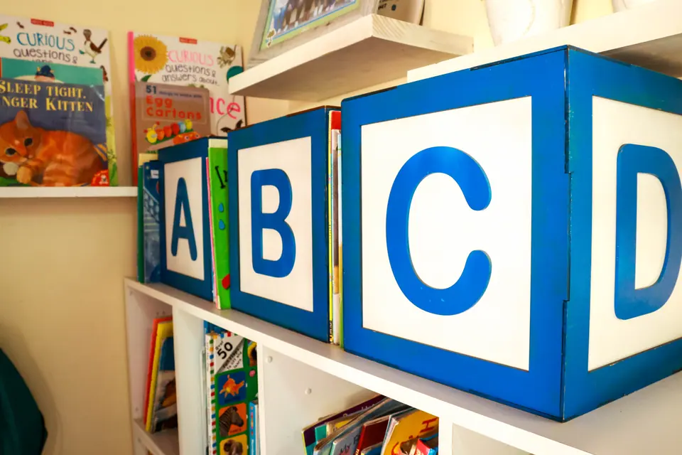 Giant ABC blocks on a classroom bookshelf filled with picture books