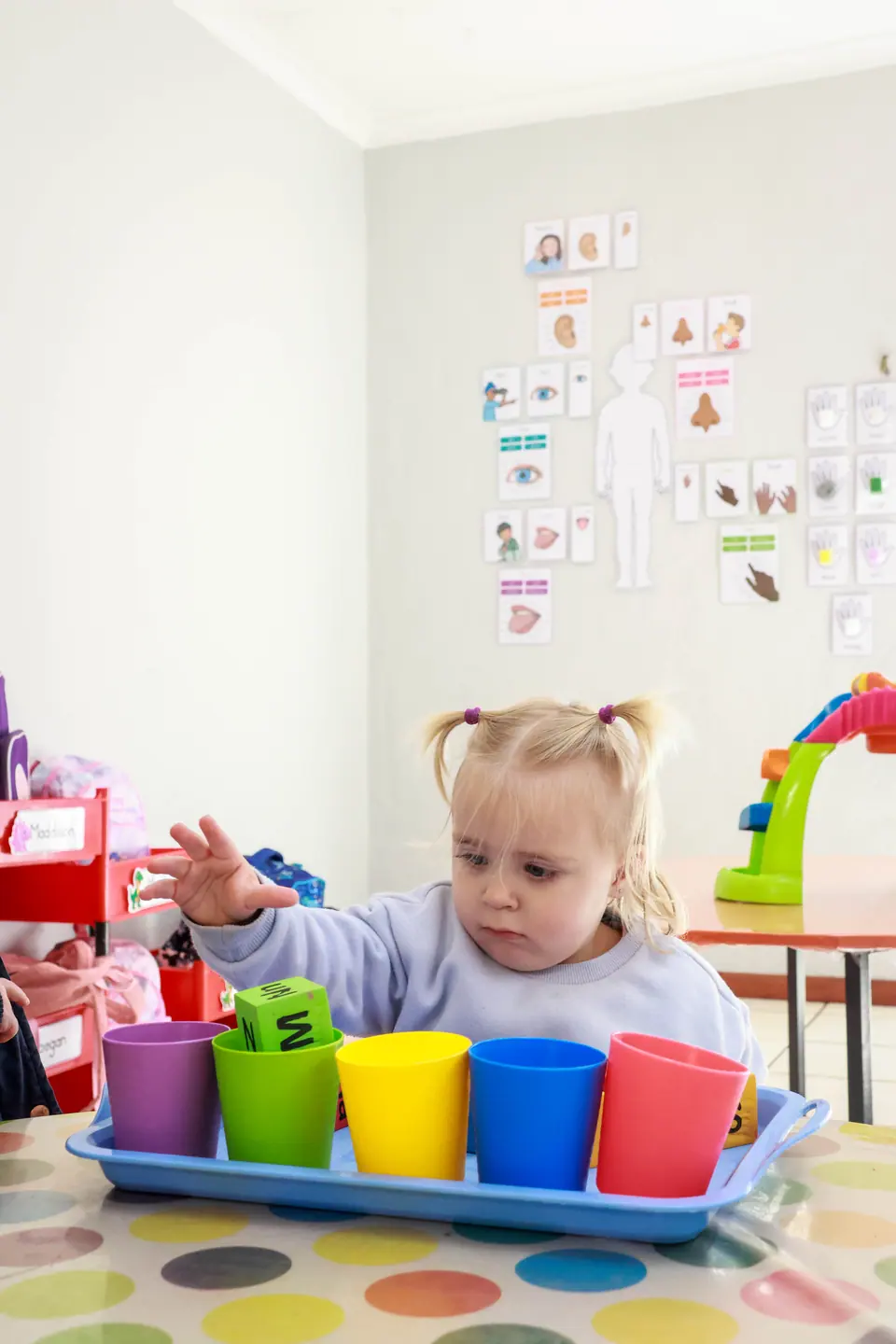 A toddler with pigtails stacking colourful cups