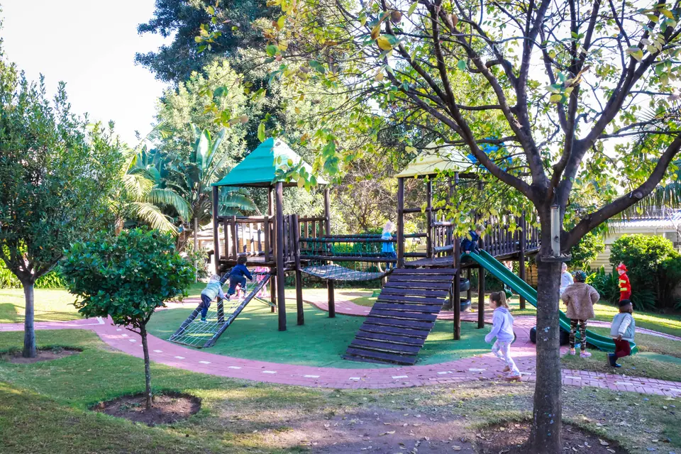 Children playing on the wooden jungle gym in the tree-lined garden