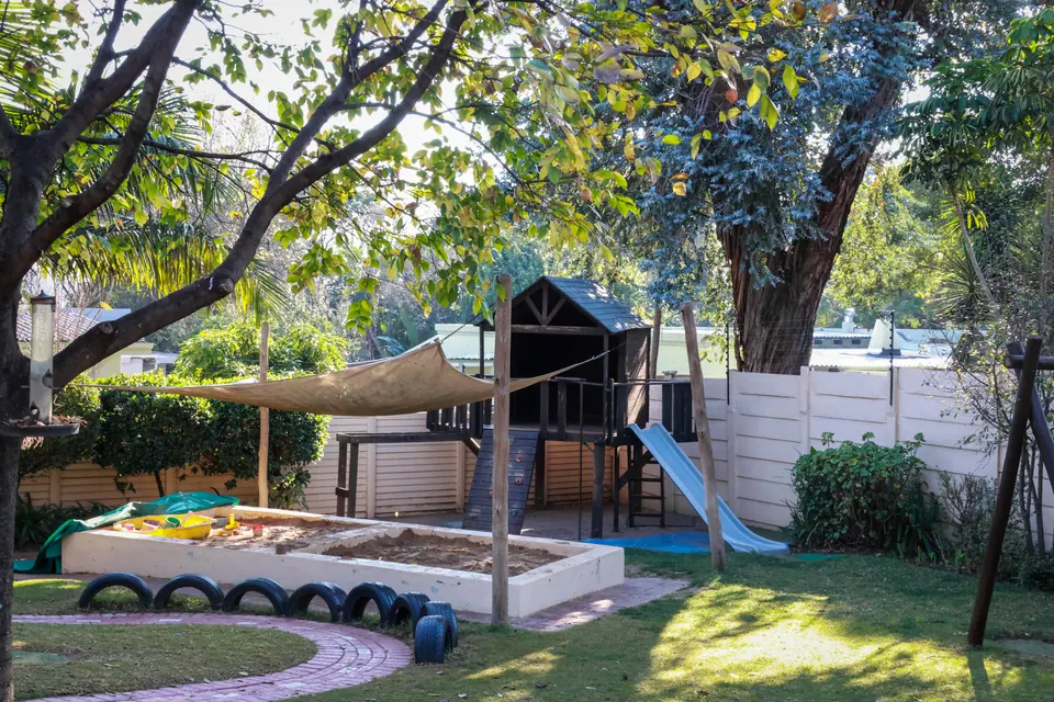 The garden with its sandpit, shade sail and wooden playhouse