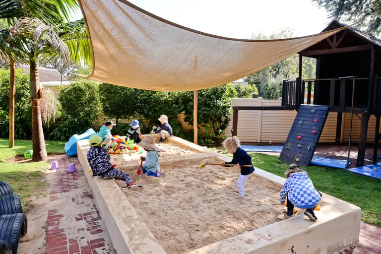 Children digging in the large sandpit under a shade sail